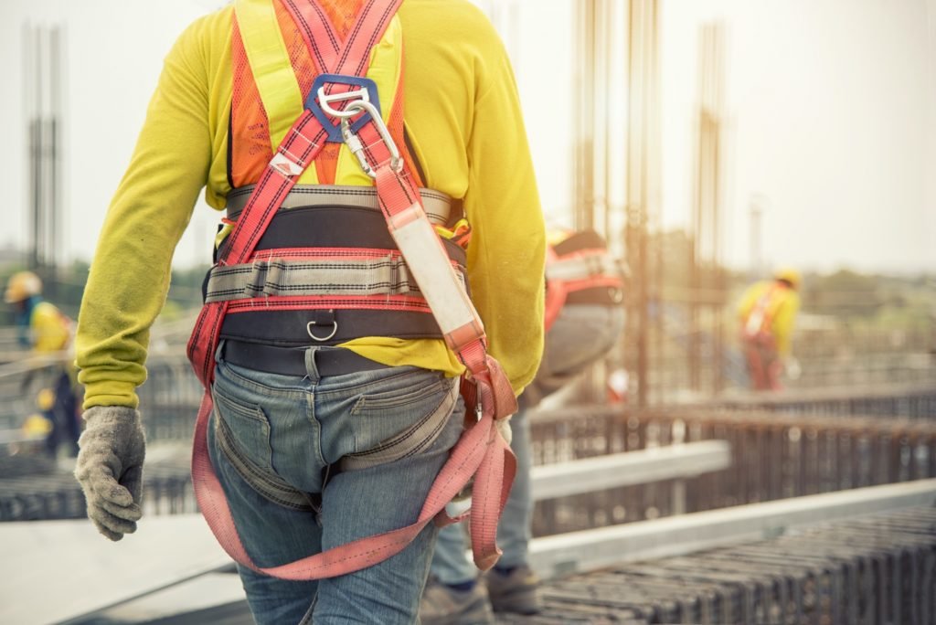 Working at height equipment. Fall arrestor device for worker with hooks for safety body harness on selective focus. Worker as a background. Construction